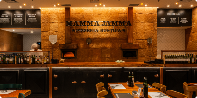 Interior do Mamma Jamma com o forno a lenha e o balcão sob o letreiro da marca