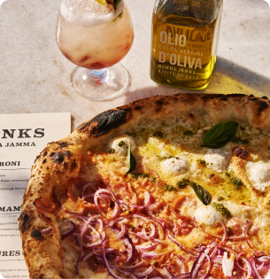 Pizza meio a meio Mamma Quaresma e Diavolleti, com drinque e azeite sobre a mesa
